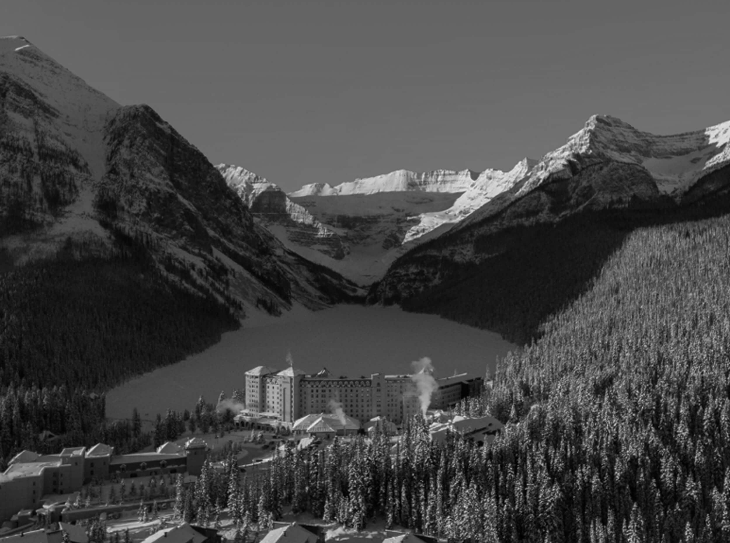 An aerial view of Fairmont Lake Louise with the lake and snow-capped mountains behind it.