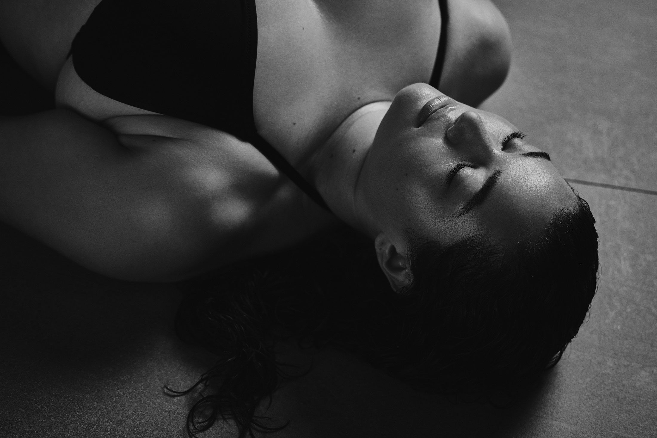 A woman in a bathing suit lying face up on a stone floor.