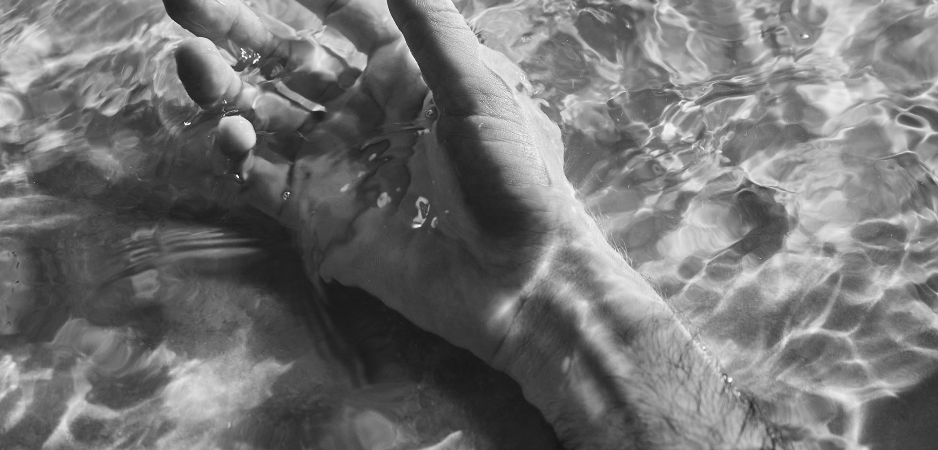 A mans hand and arm floating in the vitality pool at BASIN Glacial Waters