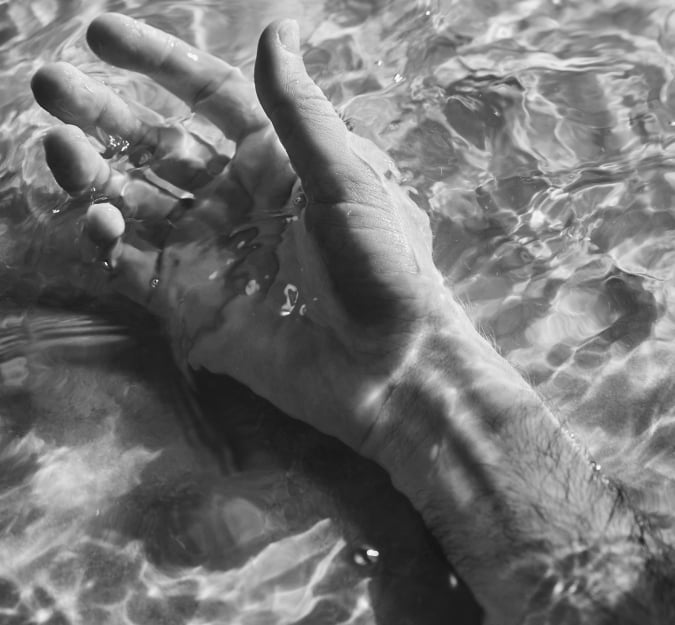 A mans hand and arm floating in the vitality pool at BASIN Glacial Waters