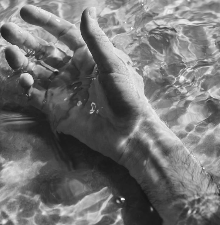 A mans hand and arm floating in the vitality pool at BASIN Glacial Waters